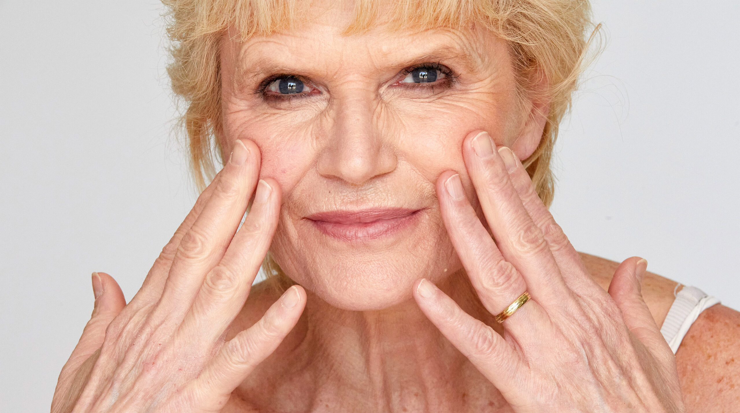 Close-up portrait of mature woman touching her skin, representing visible signs of skin aging
